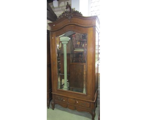 An oak armoire, the moulded arched cornice with carved pediment over a three quarter length bevelled edge mirror panelled doo