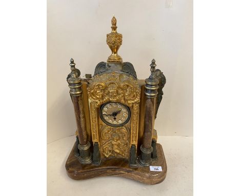 A German mantle clock, the circular face surmounted within an ornate gilded/ormolu embossed rococo panel, flanked by circular