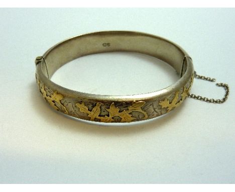 A SILVER HINGED BANGLE, with gold  coloured decorative detail