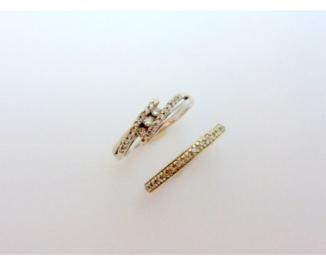 TWO DIAMOND RINGS, the first a full band diamond eternity ring, the second designed as three brilliant cut diamonds within a 