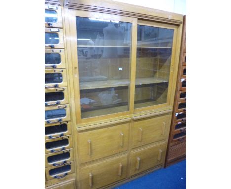 A LIGHT OAK WALL STANDING SHOP DISPLAY CABINET, with double sliding glass doors above four large drawers