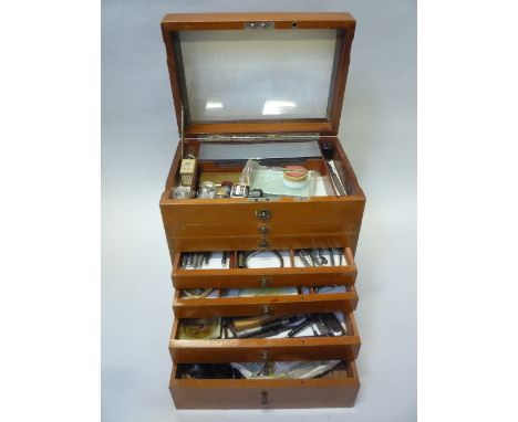 A DENTISTRY CABINET, with six drawers and a top hinged compartment containing dental instruments, with a vintage foot operate