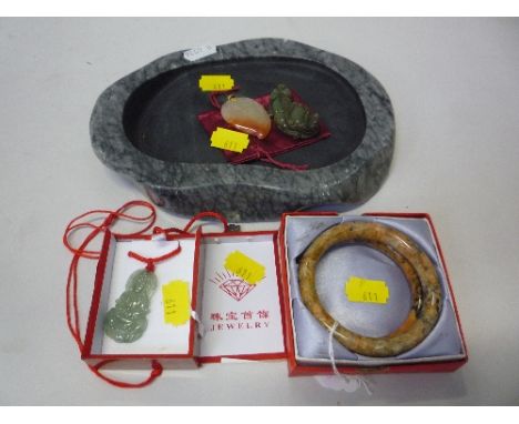 A PAIR OF RUSSET JADE BANGLES, together with a dark green jade figure of a dragon clutching a seal, a russet streaked white j