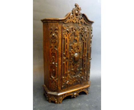 A Black Forest Miniature Oak Armoire with a Fret Work Door and Carved Cresting, raised upon bracket feet, 31 cms high