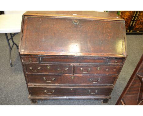 A George II oak bureau, the fall front with fitted interior above two slides, two short and two long craduationed cockbeaded 