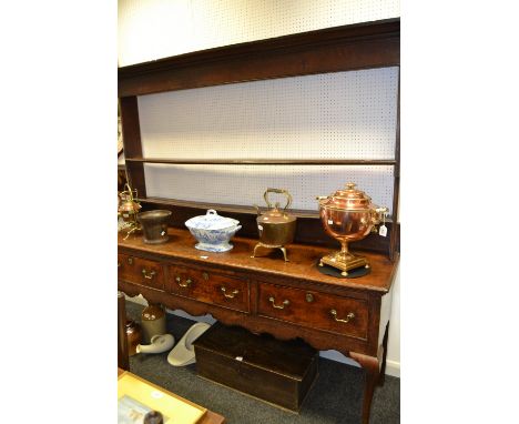 A George I oak dresser, open two shelf plate rack, the base fitted with three cockbeaded drawers, shaped apron, cabriole fore