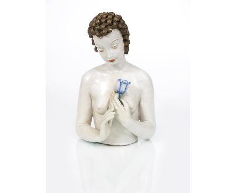 A rare Goldscheider Pottery freestanding model of a woman, model no.7543, half length, modelled holding a blue tulip flower t