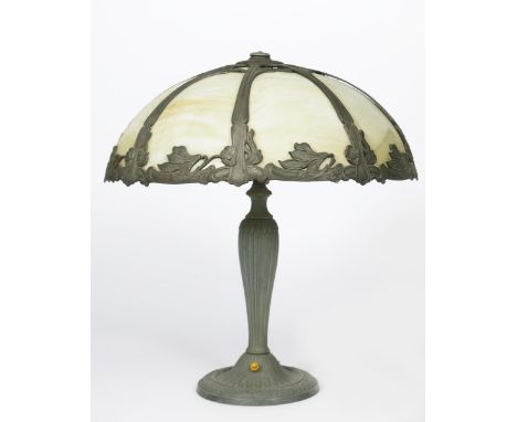 A patinated metal table lamp, probably American, shouldered base on flaring foot, cast in low relief with foliate panels, the