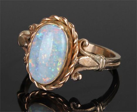 9 carat gold opal ring, set with an oval opal, rope twist mound and scroll shoulders, ring size O