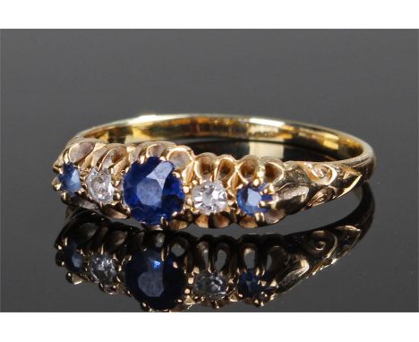 Yellow metal diamond and sapphire ring, with three sapphires and two diamonds to the mount, scroll shoulders, ring size T