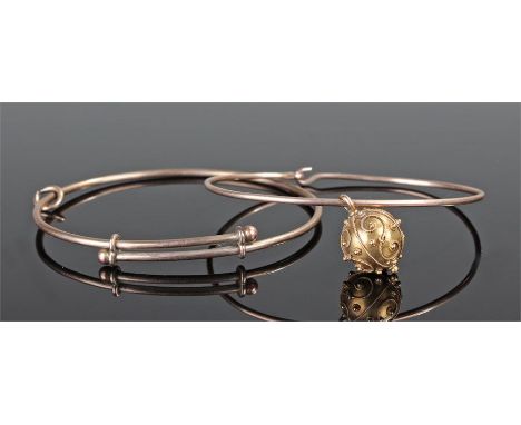 Two yellow metal bangles, the first with ball finials, the second with a drop ball pendant, total weight 14.2 grams