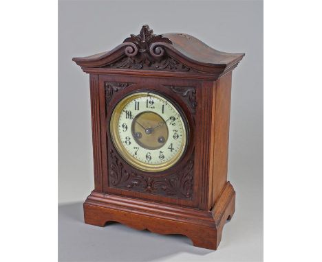 Early 20th Century mahogany mantel clock, the undulating top with swag and acanthus leaf decoration, circular glazed door and