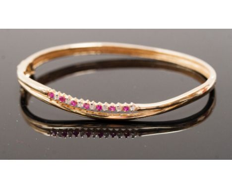 An 18ct gold Bangle claw set row of alternate rubies and brilliant-cut diamonds to the front, approx. 13.5 gms