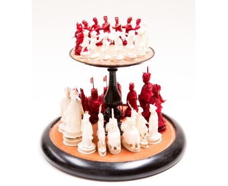 A Chinese ivory chess set, circa 1900 in white/red, housed in a glass dome covering base and shelf 