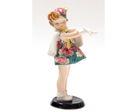 A Myott Art Deco Goldscheider figurine, modelled as a girl standing wearing a floral patterned hat and matching dress, black 