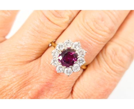 Ruby and diamond cluster ring, the oval cut ruby of approx. 2cts, set in a stepped claw mount and bordered with ten brilliant