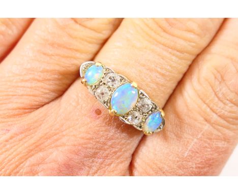 Opal and diamond cluster ring, having three oval cabochon opals dispersed with four old cut diamonds, total diamond weight es