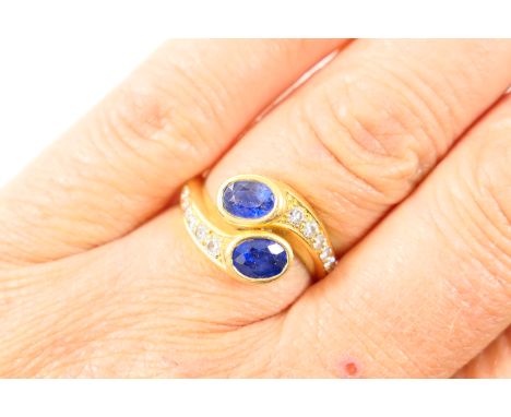 Sapphire and diamond snake's head crossover ring, set with two oval cut sapphires of approx. 0.5ct each, and channel set to t