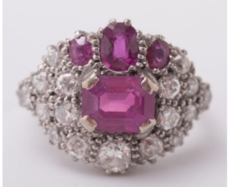 A ruby and diamond circular cluster ring:, the central, rectangular ruby below three smaller, graduated, oval rubies, within 
