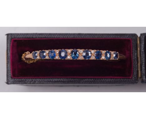 A gold, sapphire and diamond hinged bangle: with graduated, oval sapphires between old-cut diamonds, in fitted case. 