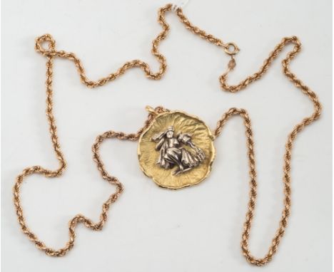 A circular pendant/brooch of textured design depicting female Arabian water carrier:, on 9ct gold rope twist chain.  
