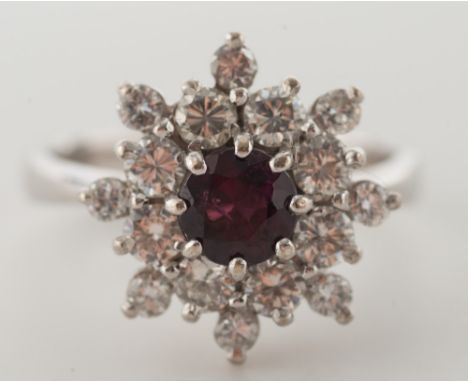 An 18ct white gold, ruby and diamond mounted cluster ring: with central circular ruby within a snowflake surround of circular