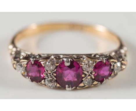 An 18ct gold, graduated ruby and diamond nine stone ring: in scroll pierced setting. 