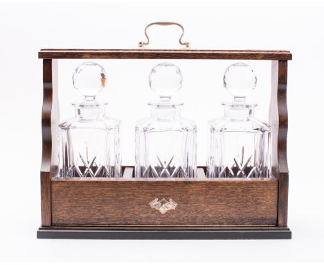 An oak and plated metal mounted tantalus in Victorian style, modern; with three fitted glass decanters with stoppers; 33cm hi