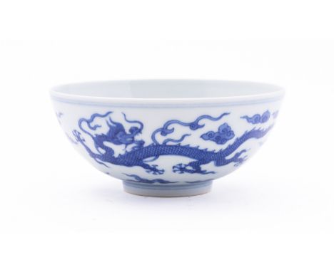 A Chinese porcelain 'Dragon' bowl the exterior painted in blue with a pair of dragons amongst cloud scrolls, with a dragon me