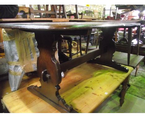 An Ercol dark elm refectory dining table of rectangular form with moulded outline raised on a pair of vase shaped column supp