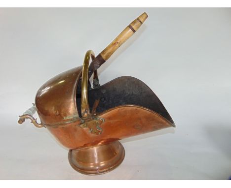An antique copper coal scuttle with applied looping handle accommodating an associated trowel, raised on a circular foot