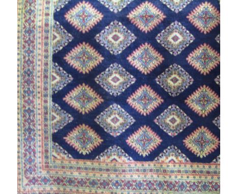 An eastern style wool work carpet with central blue ground interspersed with medallions in shades of pink, white and pale blu