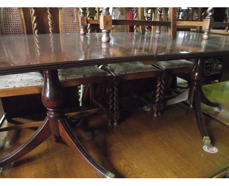 A reproduction Regency style mahogany twin pillar dining table with single additional leaf, reeded outline and rounded corner