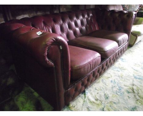 A three seat Chesterfield sofa with maroon leather upholstered finish with button detail and loose squab seat cushions