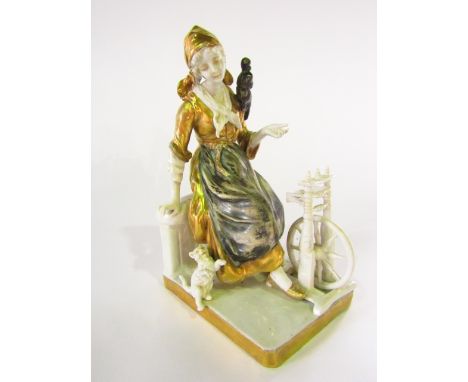 An early 20th century continental figure of a young woman seated at a spinning wheel and accompanied by a kitten, with painte