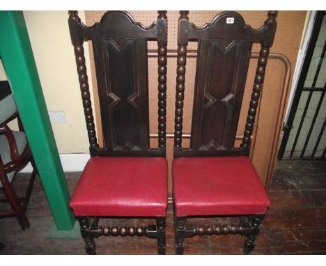 A pair of Edwardian oak side chairs with panelled backs and bobbin moulded supports with upholstered seats