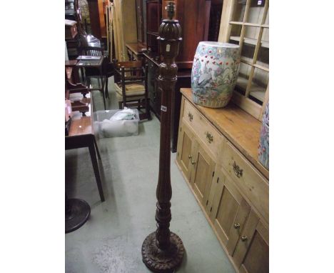 A walnut standard lamp with carved foliate and partially reeded stem and domed disc shaped platform base with further carved 