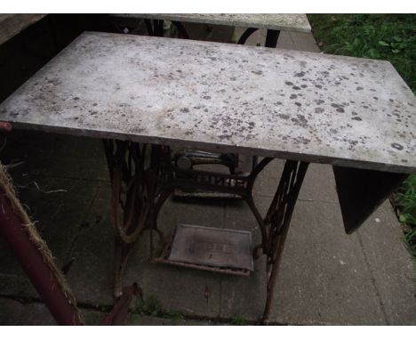 Two vintage cast iron Singer treadle sewing machine bases, later adapted as garden tables, with weathered rectangular marble 