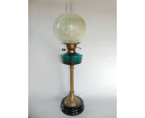 A Victorian oil burning lamp with fluted brass column raised on an ebonised base supporting a turquoise glass fount beneath a