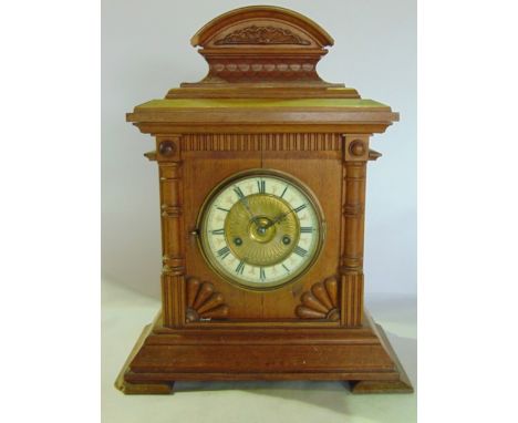 A late 19th century oak bracket clock with split spindle mouldings set beneath an arched mount enclosing an eight day strikin