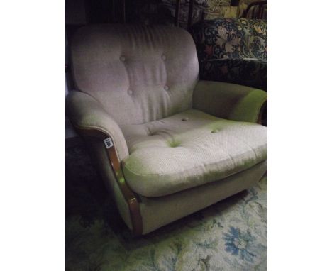 A low lounge chair, by Ercol, with swept arms and oatmeal coloured upholstery with buttoned back and squab cushion, within a 