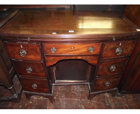 An early 19th century mahogany bow front kneehole dressing table fitted with an arrangement of seven drawers and central cupb