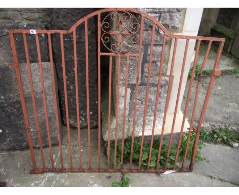 A pair of cast iron driveway entrance gates, partially arched, with vertical rails and circular scrollwork ornamental panels,