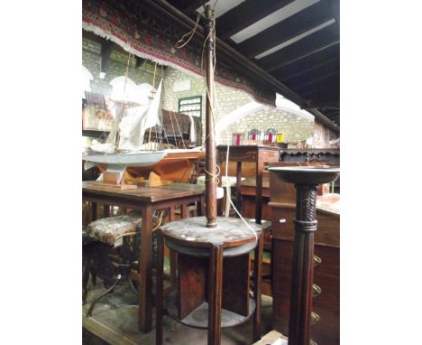An early 20th century oak standard lamp with turned column, raised on a circular platform and four moulded supports flanking 