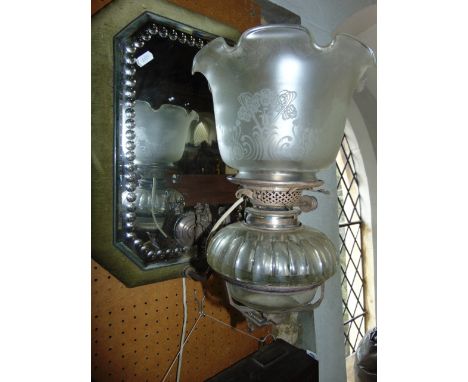 A wall mounted oil burning lamp (electric) with a Hinks burner and clear glass fount, set within an adjusting cast metal fram