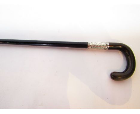 An ebonised tapering walking cane with crooked horn handle and chased silver collar with initialled cartouche dated 1924, vin