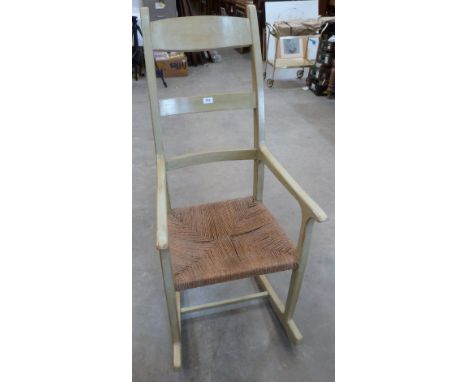 A painted rocking elbow chair with ladder back and rush seat.