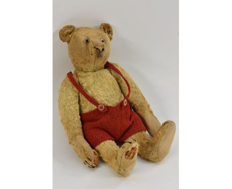 An early 20th century Steiff gold plush bear, tapering nose, glass eyes, centre seam body, stitched claws, pad feet, button t