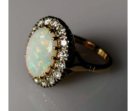 An oval opal cluster ring with sixteen round brilliant-cut diamonds, approximate total weight 1.20 carats, opal 13mm x 10mm x