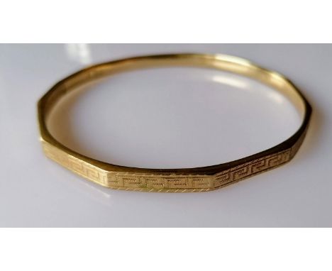 A 9ct yellow gold bangle with faceted decoration, marks rubbed, 12.5g